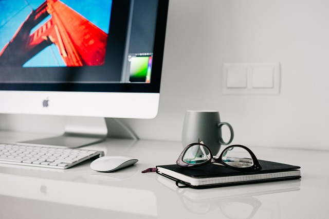 Computer with mouse, glasses and book